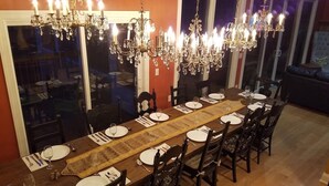 Un comedor con una larga mesa de madera dispuesta para una comida, rodeada de sillas.