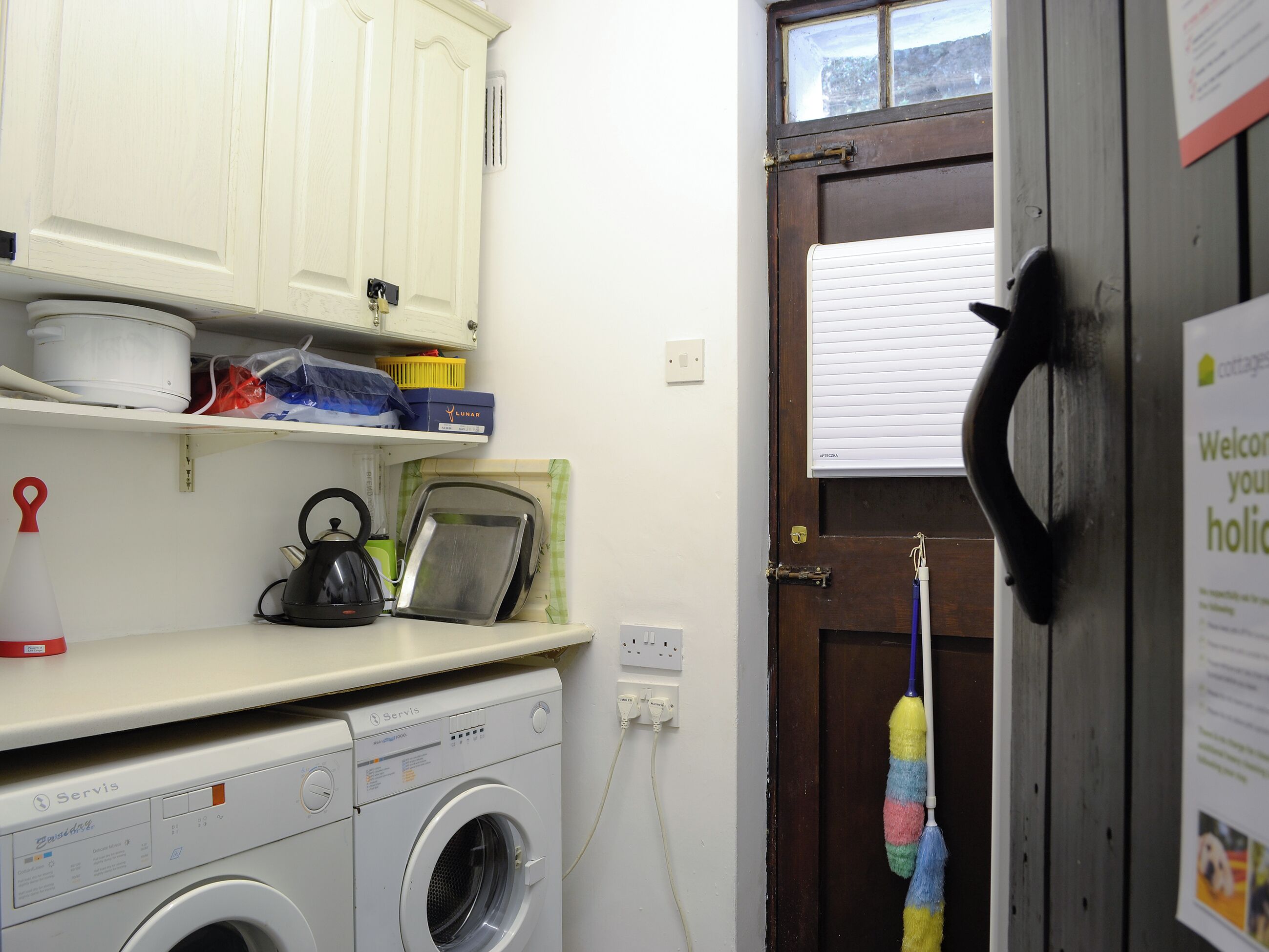 A laundry area with a washing machine, a kettle, and a drying rack.