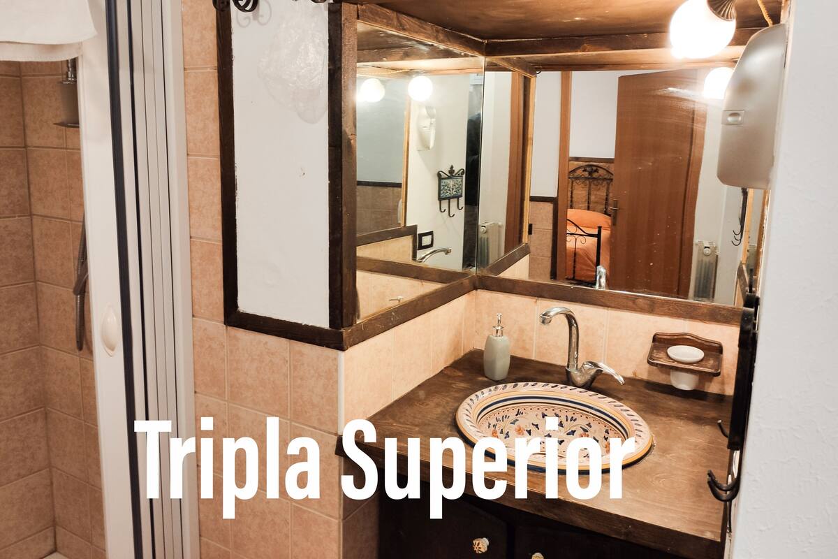 Un baño con tocador de madera, lavabo con recipiente decorativo, espejo y perchero para toallas.