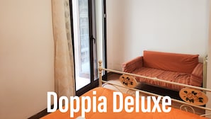 Una habitación con balcón, sofá y cama con cabecera.