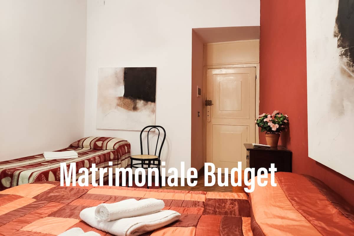 Una habitación con cama, una silla, una puerta y un cuadro en la pared.