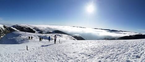 Paesaggio montano innevato con cieli sereni e alcune persone che camminano.