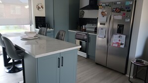 Een moderne keuken met een centraal eiland, een ingebouwde oven en een koelkast van roestvrij staal.