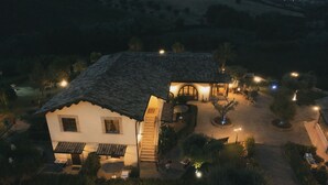 Una casa de dos pisos con techo de tejas, una escalera que conduce al nivel superior y una entrada bien iluminada.