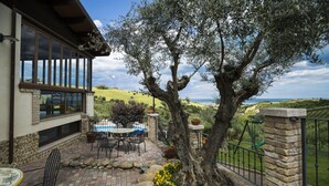 Un patio con una mesa y sillas, un muro de piedra y vistas al paisaje.