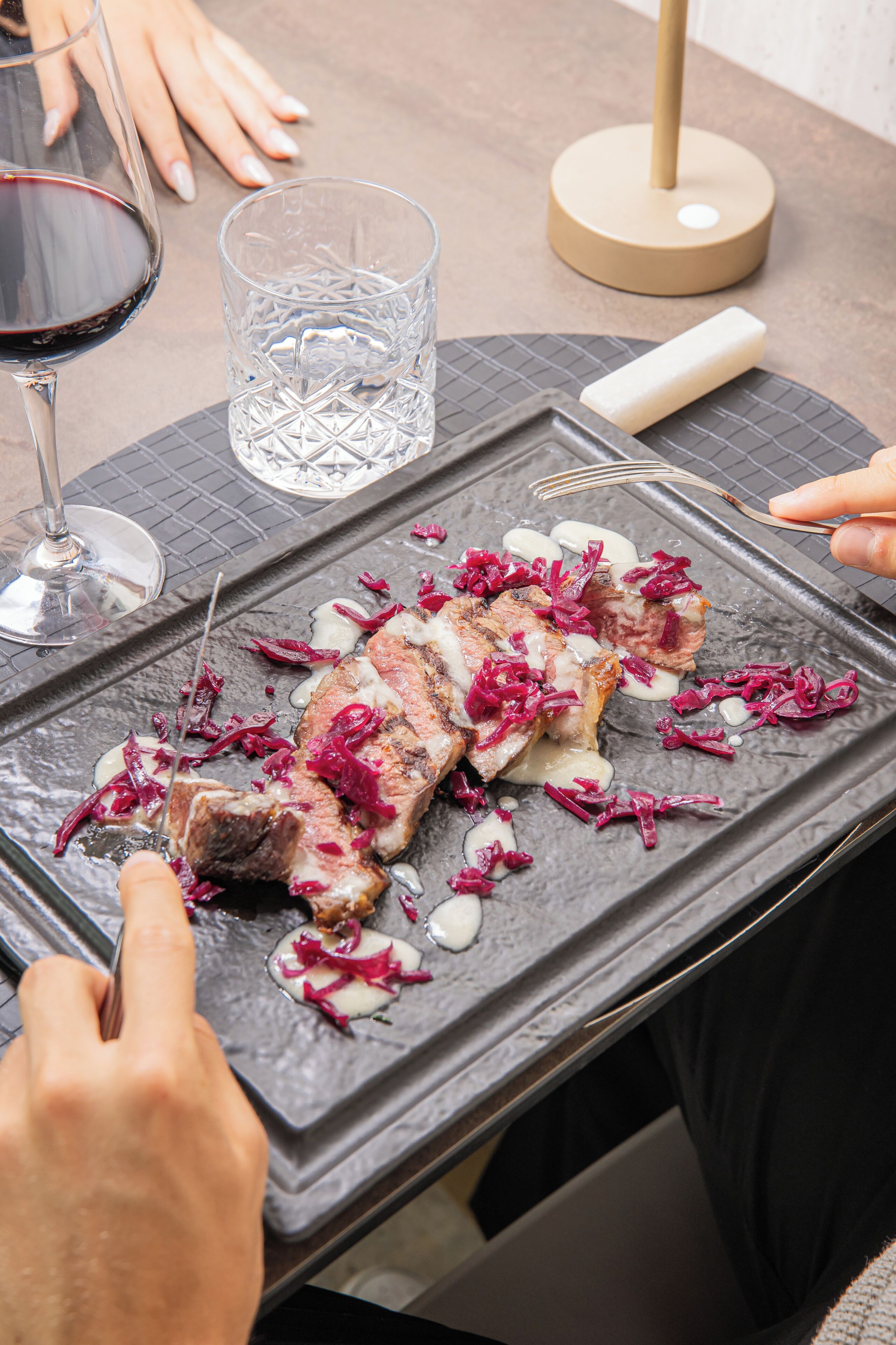 Ein Esstisch mit Essen, einem Weinglas mit Rotwein und einer Kerze.