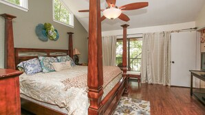Ein Bett mit Baldachin, ein Deckenventilator, ein Nachttisch aus Holz und eine Nachttischlampe.