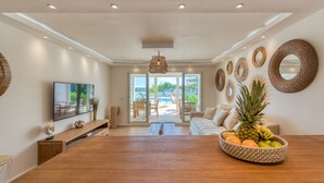 A spacious living area with a wooden coffee table, a fruit bowl, and a television on a wooden stand. - Six View - Beach Front Apartment (saint martin)