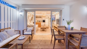 A spacious living area with a wooden floor, a sofa set, a dining table, and chairs. - Six View - Beach Front Apartment (saint martin)