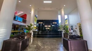 Un vestíbulo amplio con techo alto, una escalera central y un área de descanso con sofás.