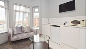 A modern kitchen with a white countertop, a microwave, and a glass coffee table. - Townhouse Plus @ 301 West Street Crewe (Crewe)