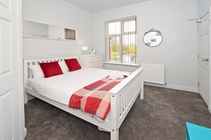 Une chambre à coucher avec un lit, une fenêtre, un radiateur et un miroir au mur.
