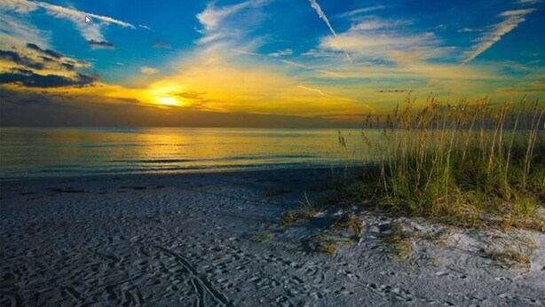Une plage au coucher du soleil, avec un ciel dégagé et un horizon lointain.