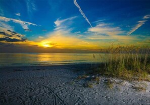 Een strand bij zonsondergang, heldere lucht en een verre horizon.