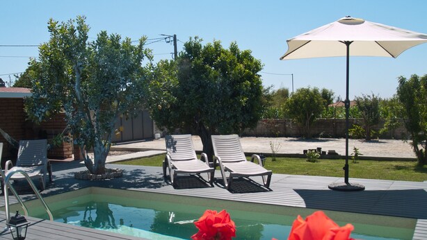 Zona de piscina amb gandules i una ombrell.