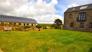 A stone house with a sloped roof and a large grassy yard. - Wonderful Wallow barn - Close  to Sennen Cove  & Porthcurno Cove & Coastal Path (Penzance)