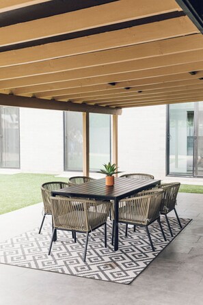 Une terrasse extérieure avec une table et des chaises, un tapis à motifs et une plante en pot.