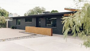 Een modern gebouw met een plat dak, grote ramen en een grindpad.