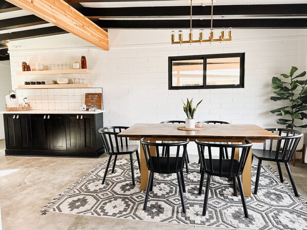 Un coin repas avec une table et des chaises en bois, une plante en pot et un mur de briques avec une fenêtre.