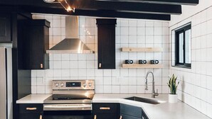 Een moderne keuken met zwarte kastjes, witte tegels, een roestvrijstalen kookplaat en een inbouwoven.