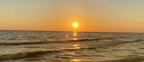 A sunset over the ocean with waves.