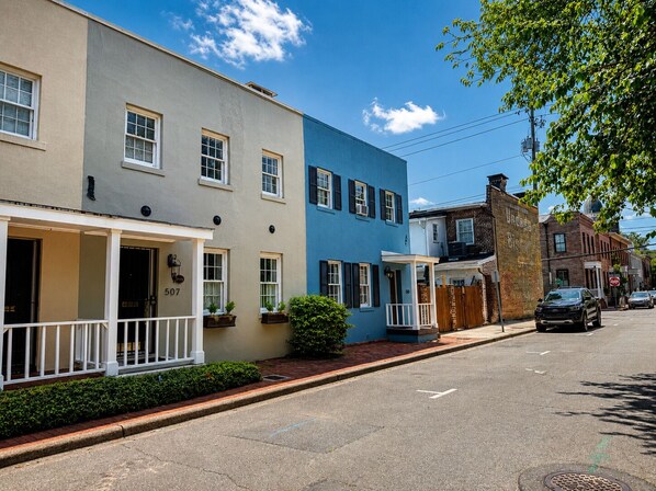 A street view with two-story houses, a clear sky, and a parked car.
