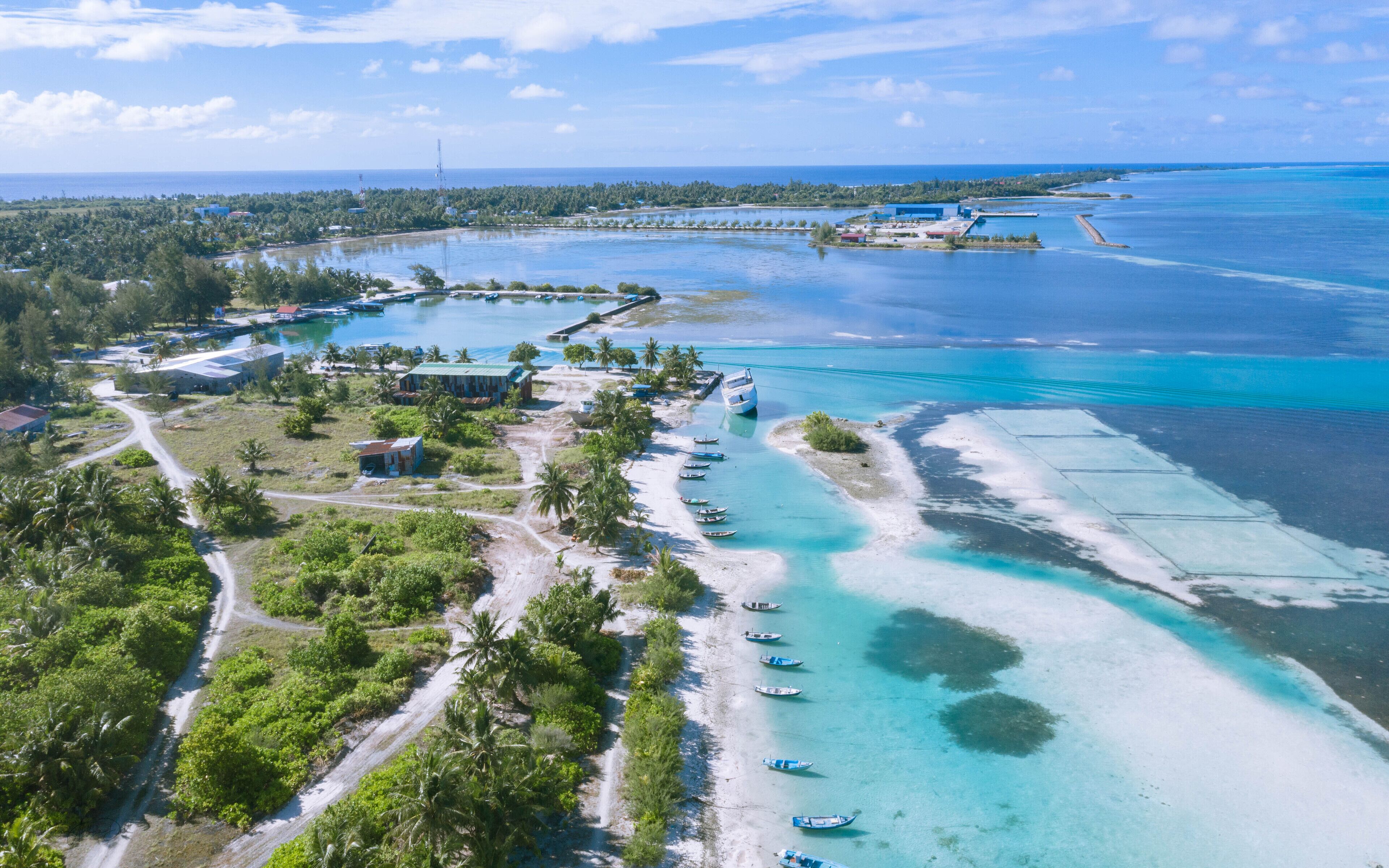 An aerial view of a coastal area with a beach, boats, and buildings.
