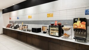 A modern kitchen area with a coffee machine, microwave, and fruit juice dispenser.