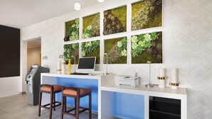 A reception area with a white desk, two bar stools, a computer, a printer, and a cash register.