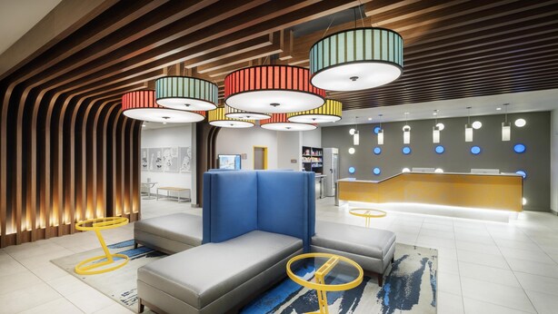 A modern lobby with a reception desk, seating area, and unique lighting fixtures.