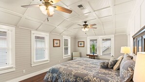 Une chambre avec un grand lit, deux ventilateurs de plafond et une fenêtre avec des stores.