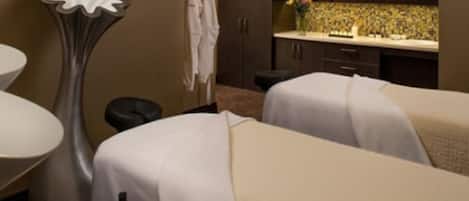 A hotel room with two beds, a bathroom with a sink and mirror, and a decorative vase.
