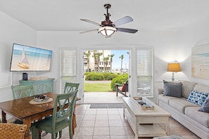 Enjoy a view of the neighborhood from the comfort of this living room, featuring a dining table, sofa, and TV.