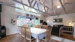 Uma sala de jantar com uma mesa, cadeiras, lareira e vista para o exterior.