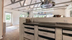 Uma cozinha moderna com ilha central, armários embutidos e teto alto com vigas aparentes.
