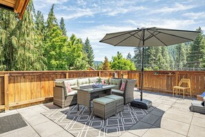 Une terrasse extérieure avec un ensemble de meubles de jardin en osier, une table et un parasol.