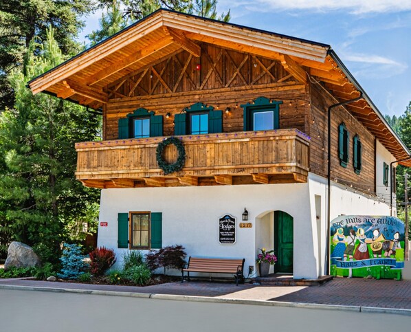 Un bâtiment traditionnel en bois, doté d’un balcon, d’un banc et d’une enseigne indiquant la présence d’un restaurant.