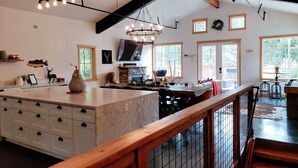 Una cocina amplia con una isla grande, vigas de madera y una araña.