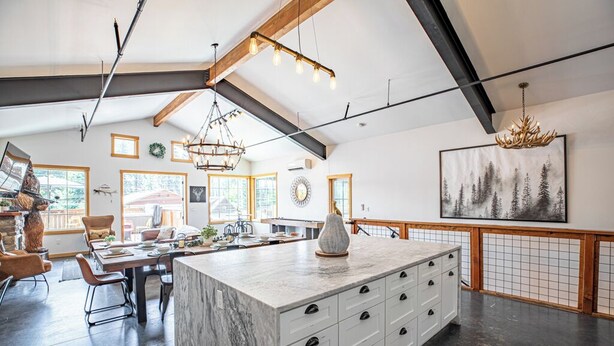 Una cocina amplia con una isla grande, vigas de madera e iluminación moderna.