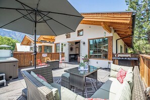 Un espace extérieur aménagé en terrasse, avec des meubles en osier, une table à plateau en verre et un barbecue.