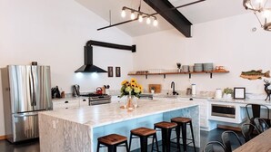 Una cocina moderna con una isla grande, taburetes de bar y un refrigerador de acero inoxidable.