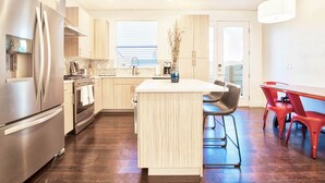 Une cuisine moderne dotée d’appareils électroménagers en acier inoxydable, d’un îlot central et d’un coin repas avec des chaises rouges.
