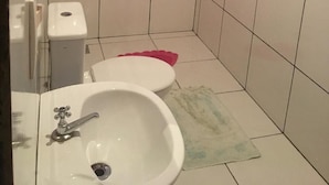 Een kleine badkamer met een witte wastafel, toilet en spiegel.