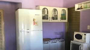Een kleine keuken met een koelkast, magnetron en kastjes.