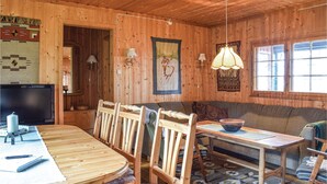 L'interno di una baita in legno con un tavolo da pranzo, sedie, un divano e una televisione.