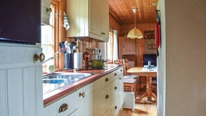 Cucina con mobili in legno, lavello e zona pranzo con tavolo e sedie.