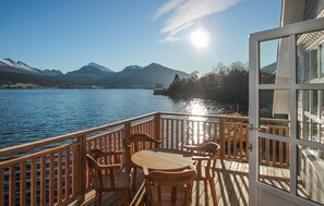 A wooden deck with a table and chairs overlooking a lake with mountains in the background. - 2 bedroom stunning apartment in Vestnes (Vestnes)