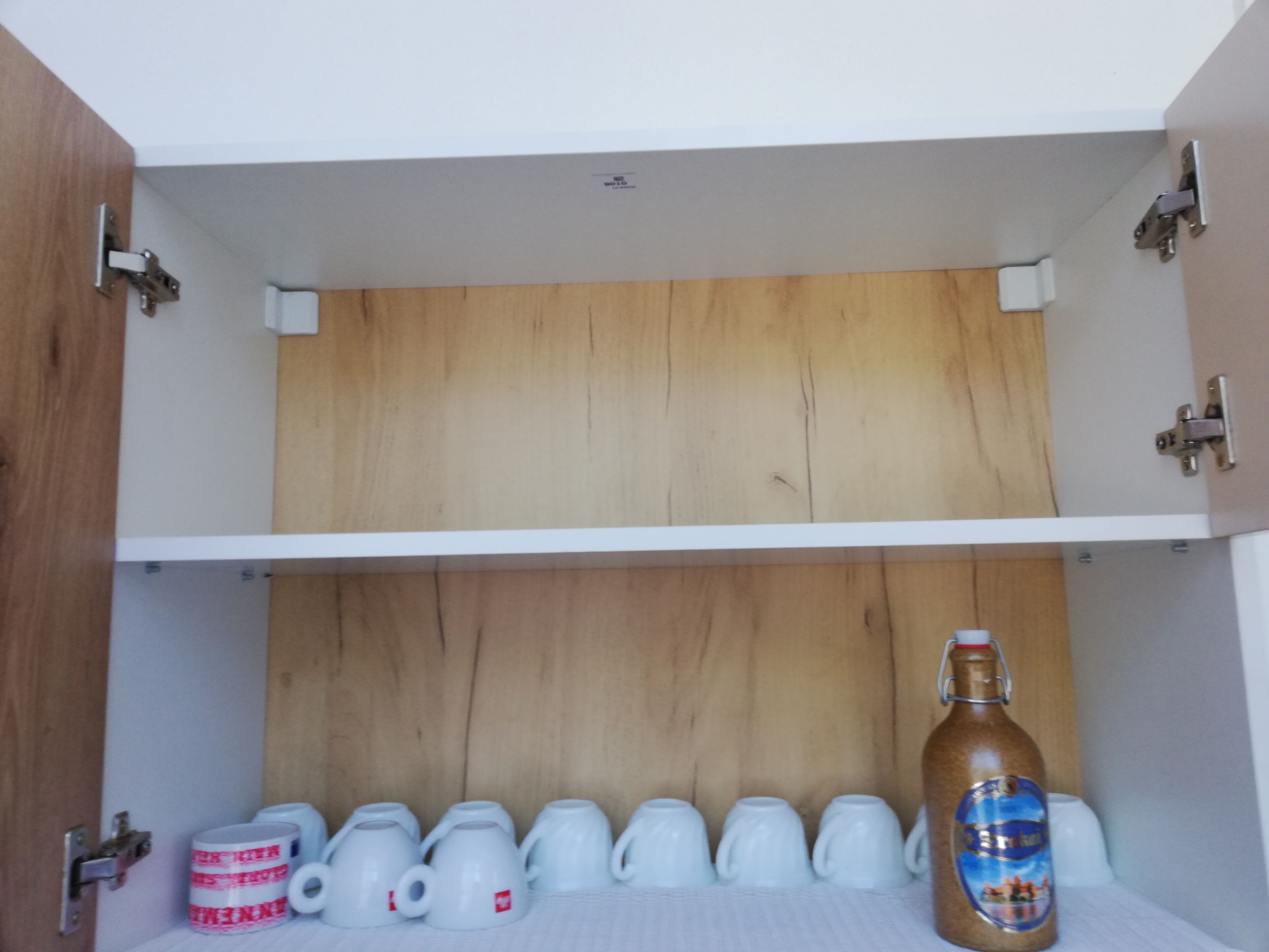A storage cabinet with multiple shelves, a wooden panel, and a bottle on the bottom shelf.
