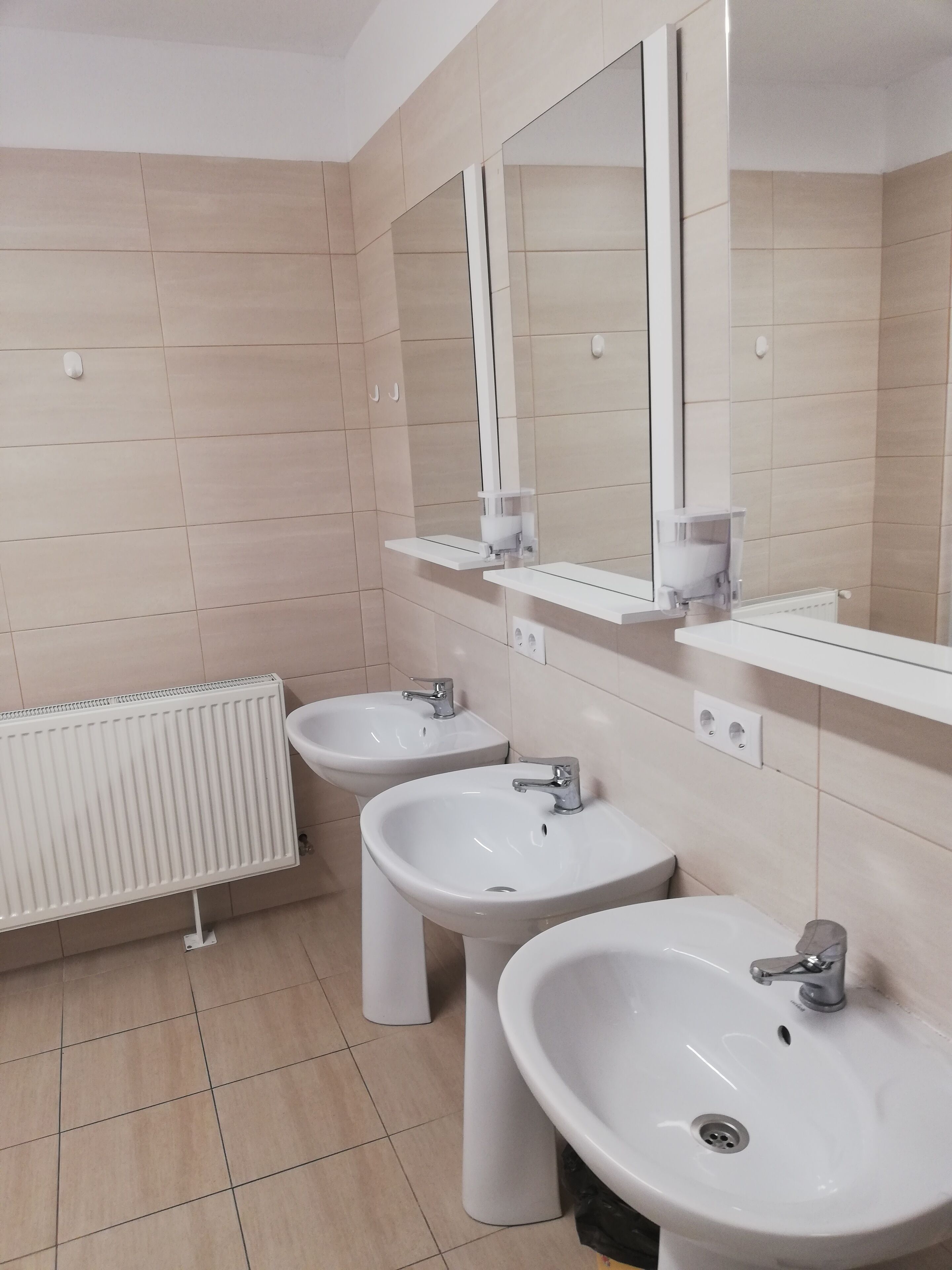 A modern bathroom with two sinks, a mirror, and a radiator.