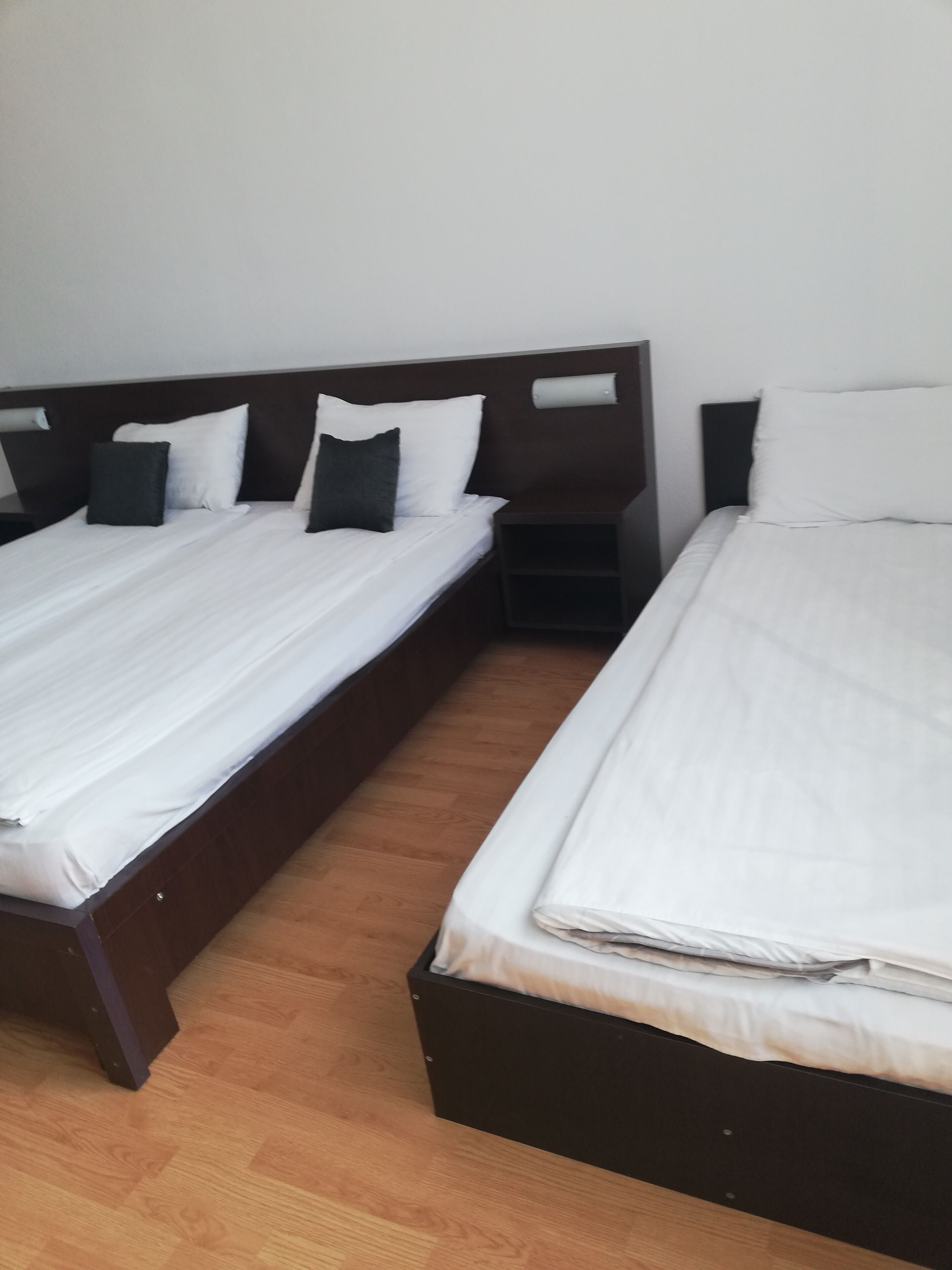Two single beds with wooden headboards, white bedding, and a wooden floor.